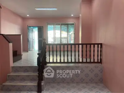 Charming pink interior with tiled floors and wooden railing, perfect for cozy living.