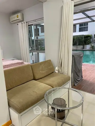 Cozy living area with poolside view and modern furnishings in a stylish apartment.