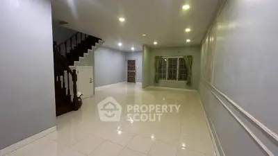 Spacious empty living room with staircase and large window, ideal for customization.