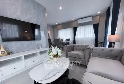 Elegant living room with modern decor, featuring a plush sofa, wall-mounted TV, and stylish dining area.