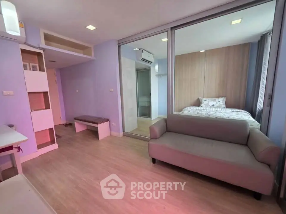 Modern studio apartment with cozy living area and stylish bedroom separated by glass partition.
