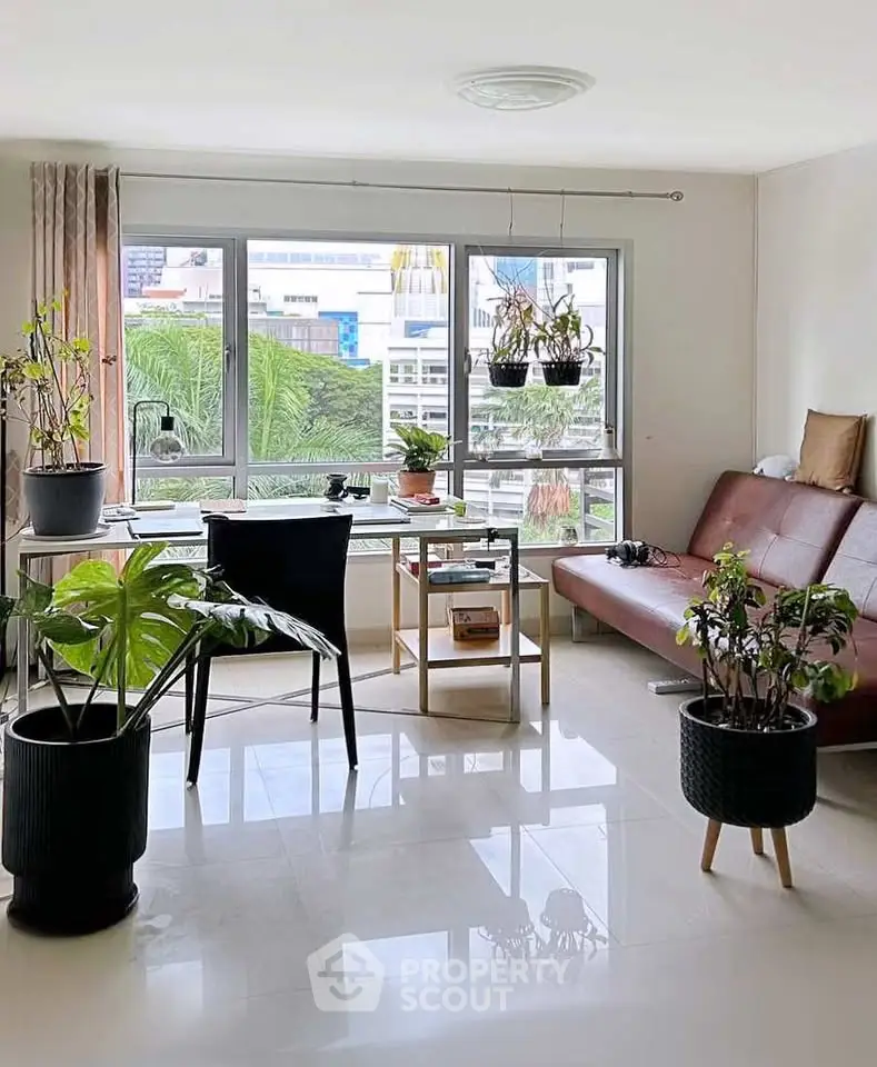 Bright living room with large windows and indoor plants, featuring modern furniture and city view.