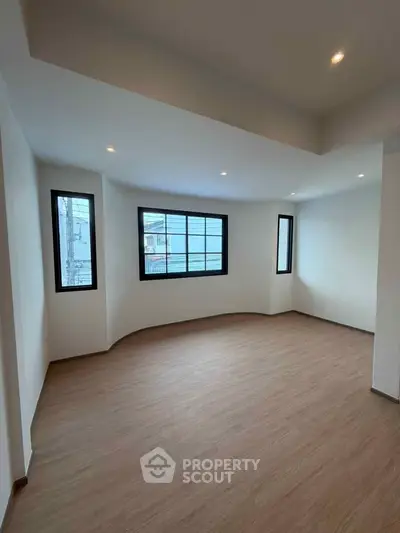 Spacious empty room with large windows and wooden flooring, perfect for customization.