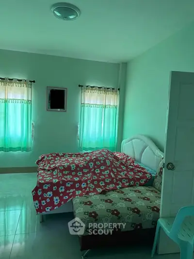 Cozy bedroom with floral bedding and natural light from two windows.
