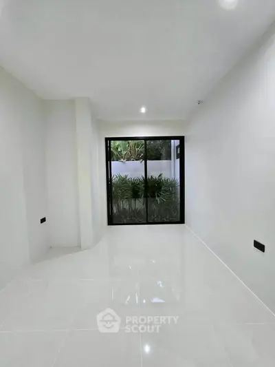Spacious minimalist room with large window and garden view, perfect for modern living.