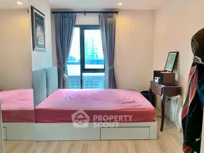 Cozy bedroom with pink bedding, large window, and modern decor in urban apartment.