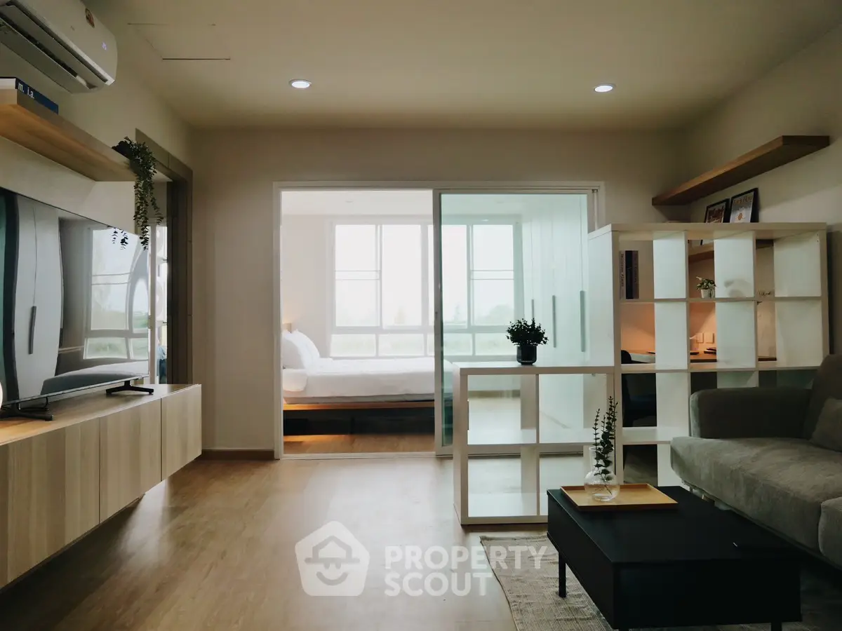 Modern living room with open layout leading to a bright bedroom, featuring stylish furniture and decor.