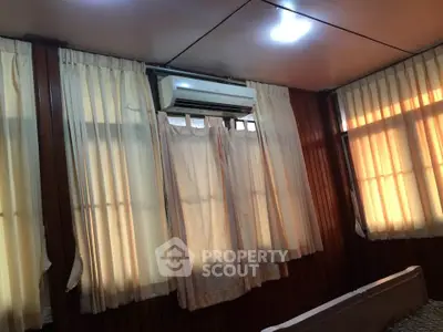 Cozy room with wooden paneling and air conditioning, featuring warm lighting and curtains.