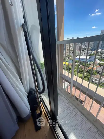 Modern apartment balcony with city view and vacuum cleaner by the window.