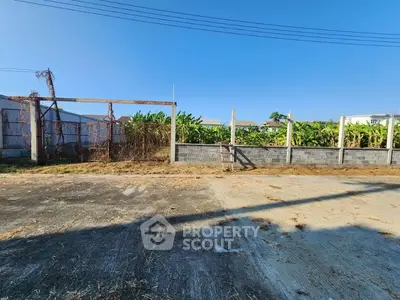 Vacant land with concrete pavement and lush greenery in the background, ideal for development.