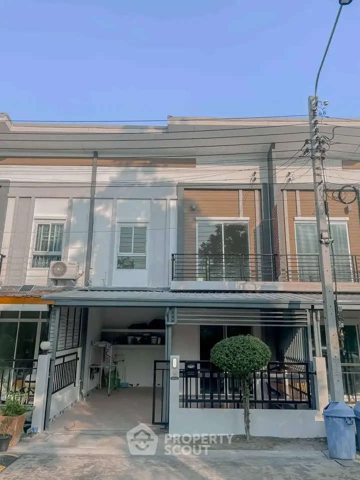 Modern townhouse exterior with balcony and parking space in a serene neighborhood.