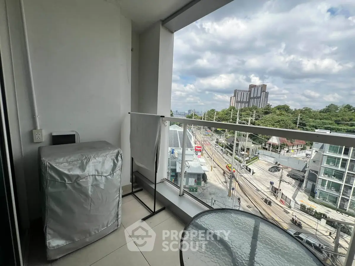 Modern balcony with city view and glass table, perfect for relaxation.