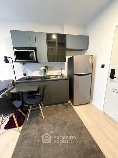 Modern compact kitchen with sleek cabinets and stainless steel fridge in cozy apartment.