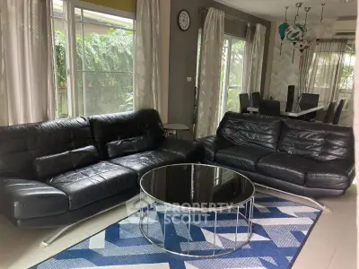 Spacious living room with modern black leather sofas and stylish dining area.