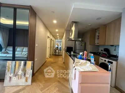 Modern apartment interior with open kitchen and cozy living area, featuring sleek design and natural light.