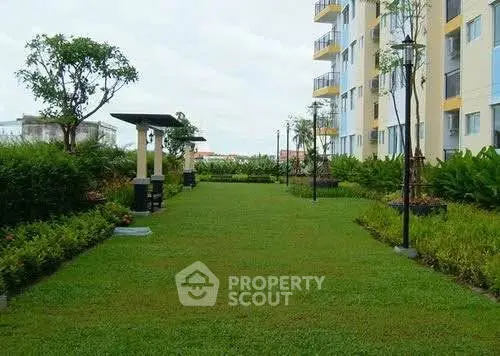 Beautifully landscaped garden area in modern apartment complex with lush greenery and outdoor seating.