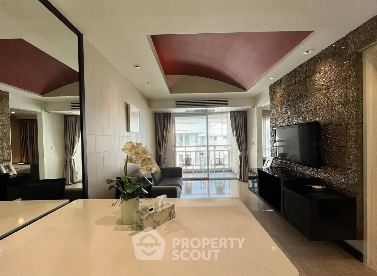 Spacious living room with modern decor and large windows leading to a balcony.