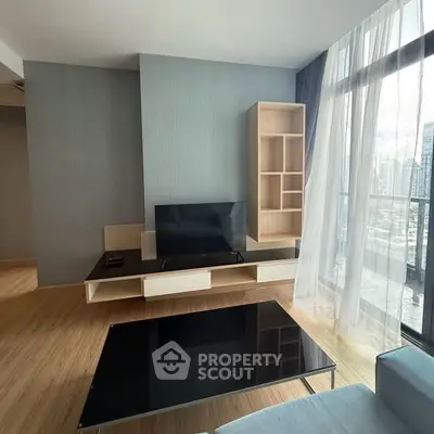Modern living room with sleek furniture and large windows offering city views.