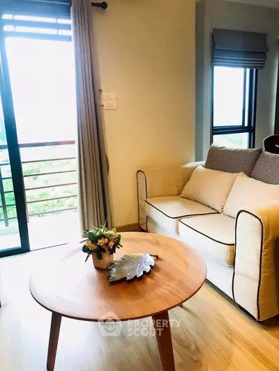 Cozy living room with natural light and balcony access, featuring a stylish sofa and wooden coffee table.