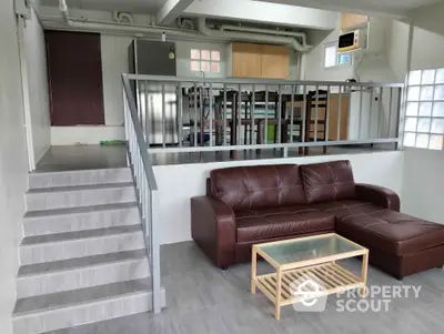 Modern split-level living room with leather sofa and glass coffee table