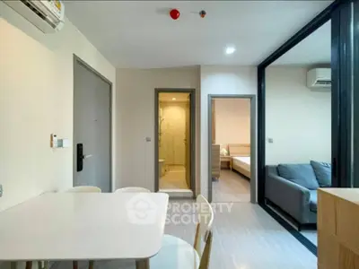Modern apartment interior with dining area, living room, and bedroom view.