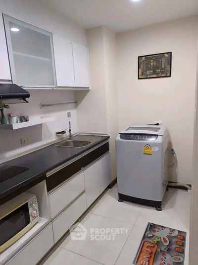 Modern kitchen with sleek cabinets and washing machine, perfect for urban living.