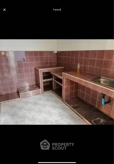 Spacious kitchen with tiled countertops and sink, ideal for culinary enthusiasts.