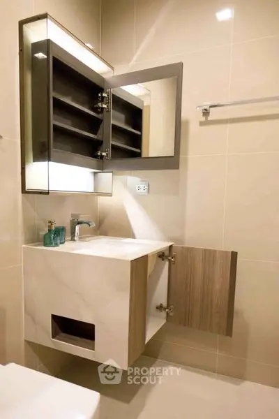 Modern bathroom with sleek vanity and mirrored cabinet, featuring elegant lighting and minimalist design.