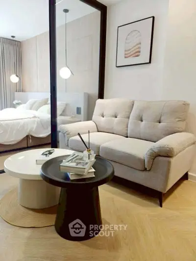 Modern living room with cozy sofa and stylish coffee tables, adjacent to a serene bedroom.