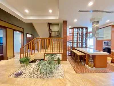 Luxurious open-plan kitchen with elegant staircase and modern design elements.