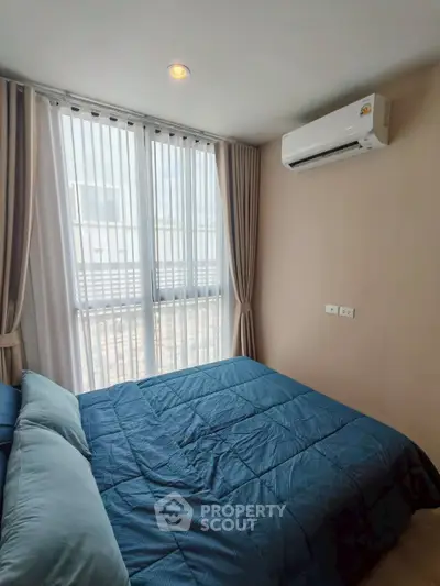 Cozy bedroom with modern air conditioning and natural light through large windows.