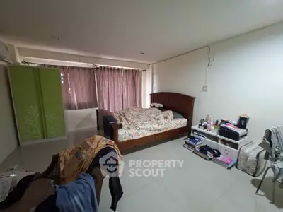 Spacious bedroom with large bed and natural light from window, ideal for cozy living.