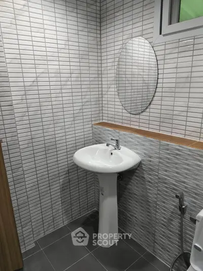 Modern bathroom with sleek pedestal sink and stylish tile design.