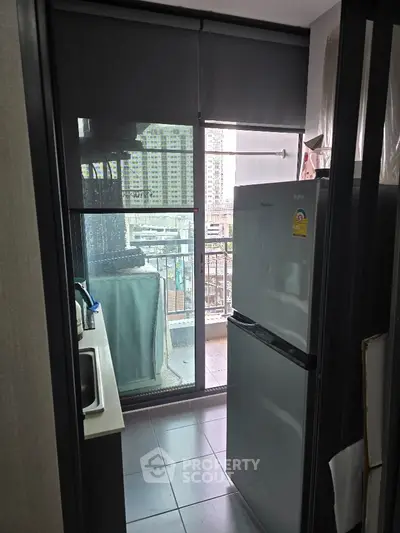 Compact kitchen with refrigerator and balcony view in modern apartment