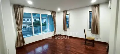 Spacious empty room with hardwood floors and large windows in modern apartment.