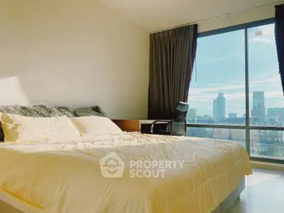 Spacious bedroom with large window offering stunning city views and ample natural light.
