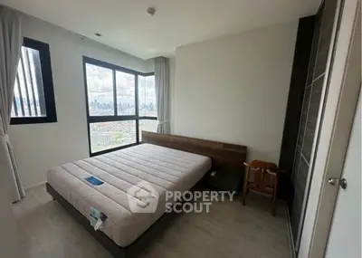Modern bedroom with large window offering stunning city view, minimalist design and ample natural light.