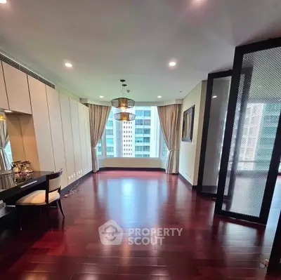 Spacious living room with hardwood floors and large windows offering city views.