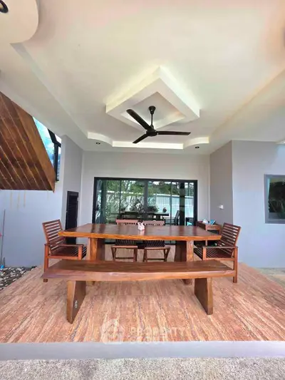 Stylish outdoor patio with wooden furniture and ceiling fan, perfect for relaxation and entertaining.