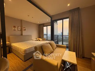 Spacious bedroom with cozy seating area and stunning city view from large windows.