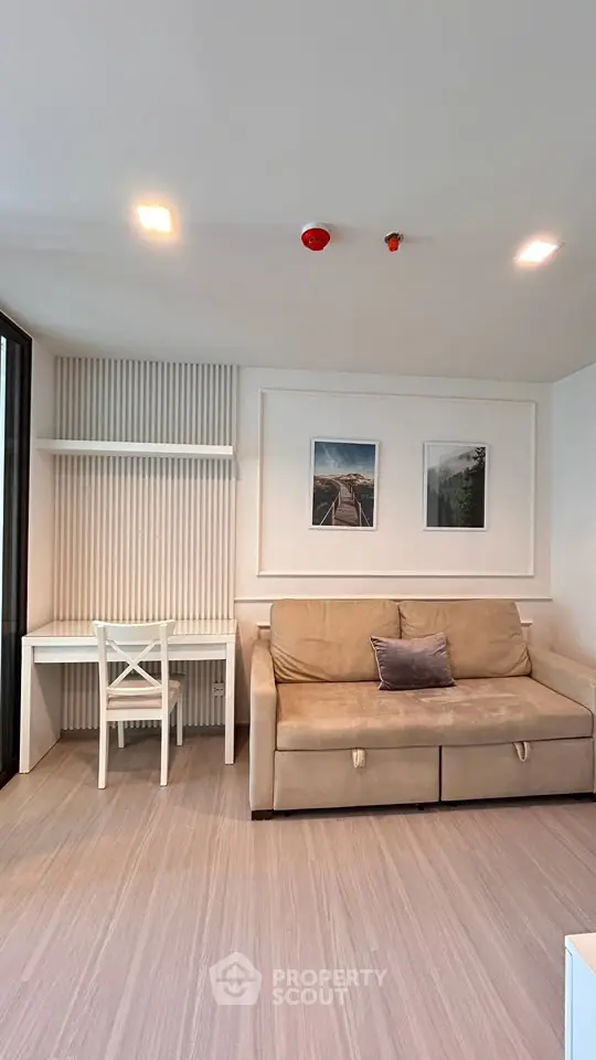 Modern living room with beige sofa, wall art, and a sleek white desk under soft lighting.