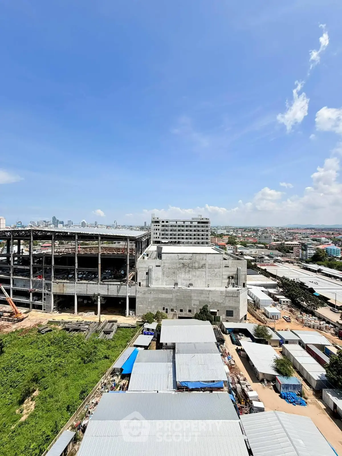 Panoramic view of urban construction site with city skyline in the background under a clear blue sky.