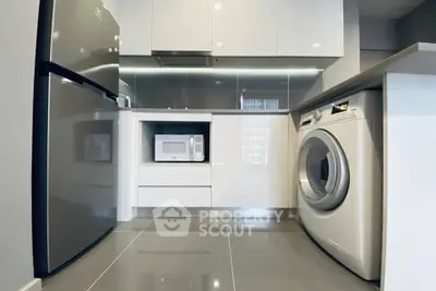 Modern kitchen with sleek appliances including fridge, microwave, and washing machine.