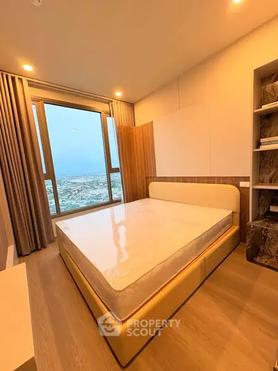 Modern bedroom with large window offering stunning city view, featuring elegant design and ample natural light.