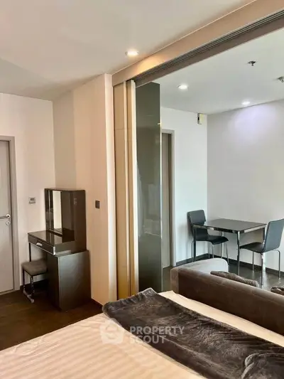 Modern apartment interior with cozy bedroom and dining area, featuring sleek furniture and stylish decor.