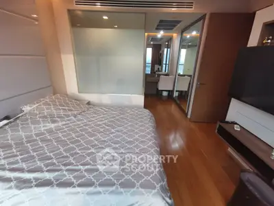 Modern bedroom with wooden flooring and stylish decor in a luxury apartment.