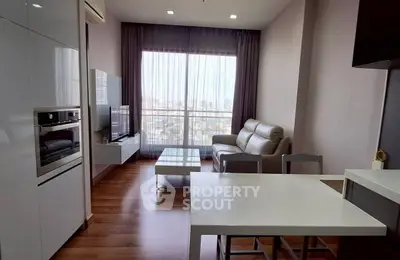 Modern living room with city view, sleek furniture, and integrated kitchen appliances.