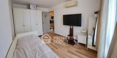 Cozy bedroom with wooden flooring, TV, and ample storage in a modern apartment.