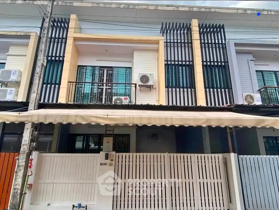 Modern townhouse exterior with balcony and gated entrance