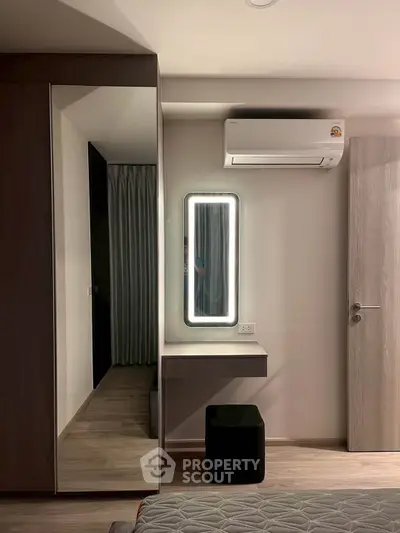 Modern bedroom with sleek design featuring a mirrored wardrobe and wall-mounted air conditioner.